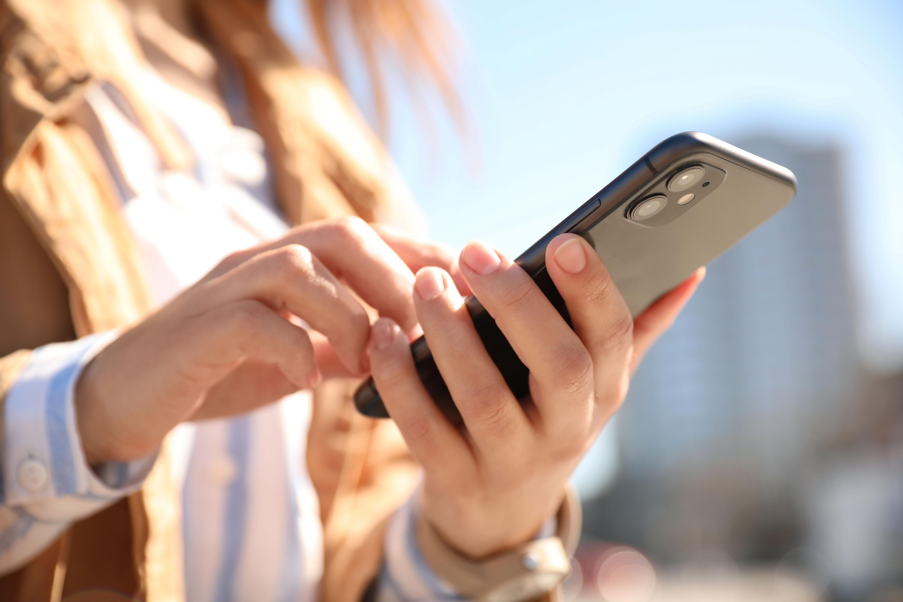 Bildausschnitt einer Frau, die ein Smartphone bedient.