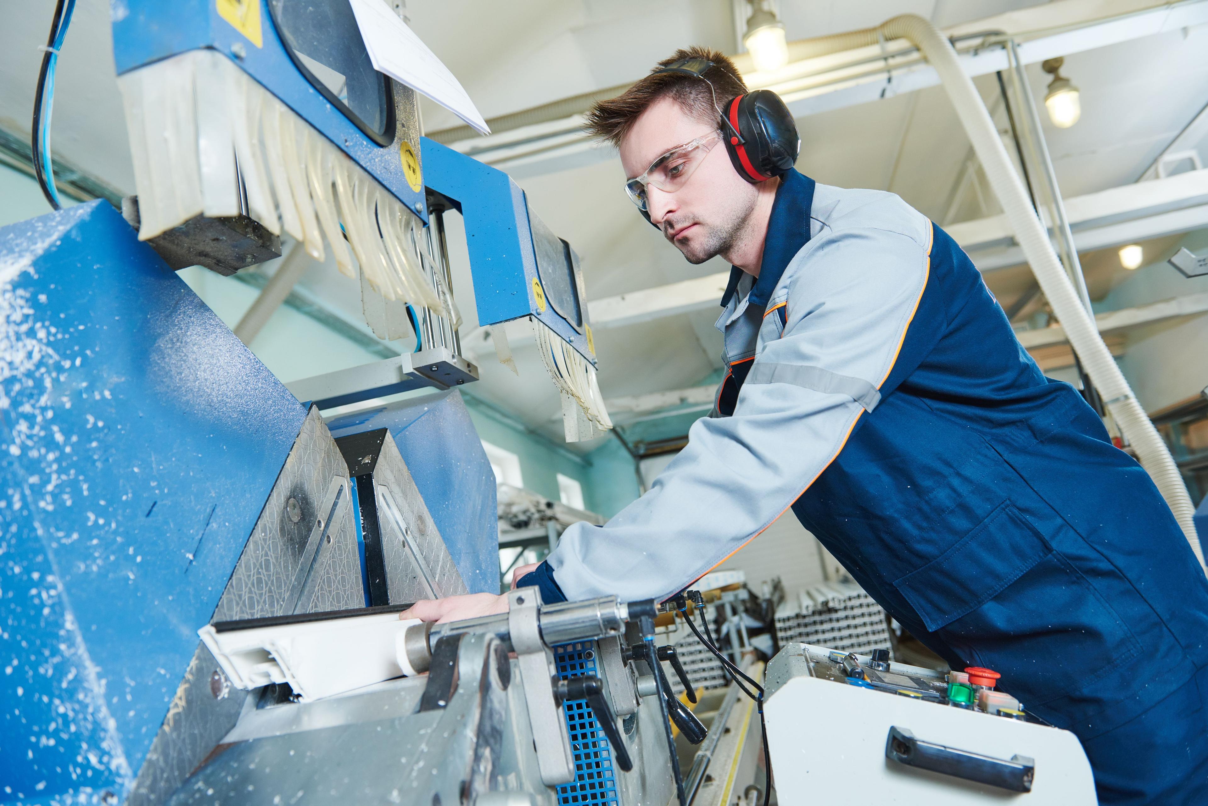Produktionsarbeiter bei der Herstellung eines Fensters an einer Industriemaschine
