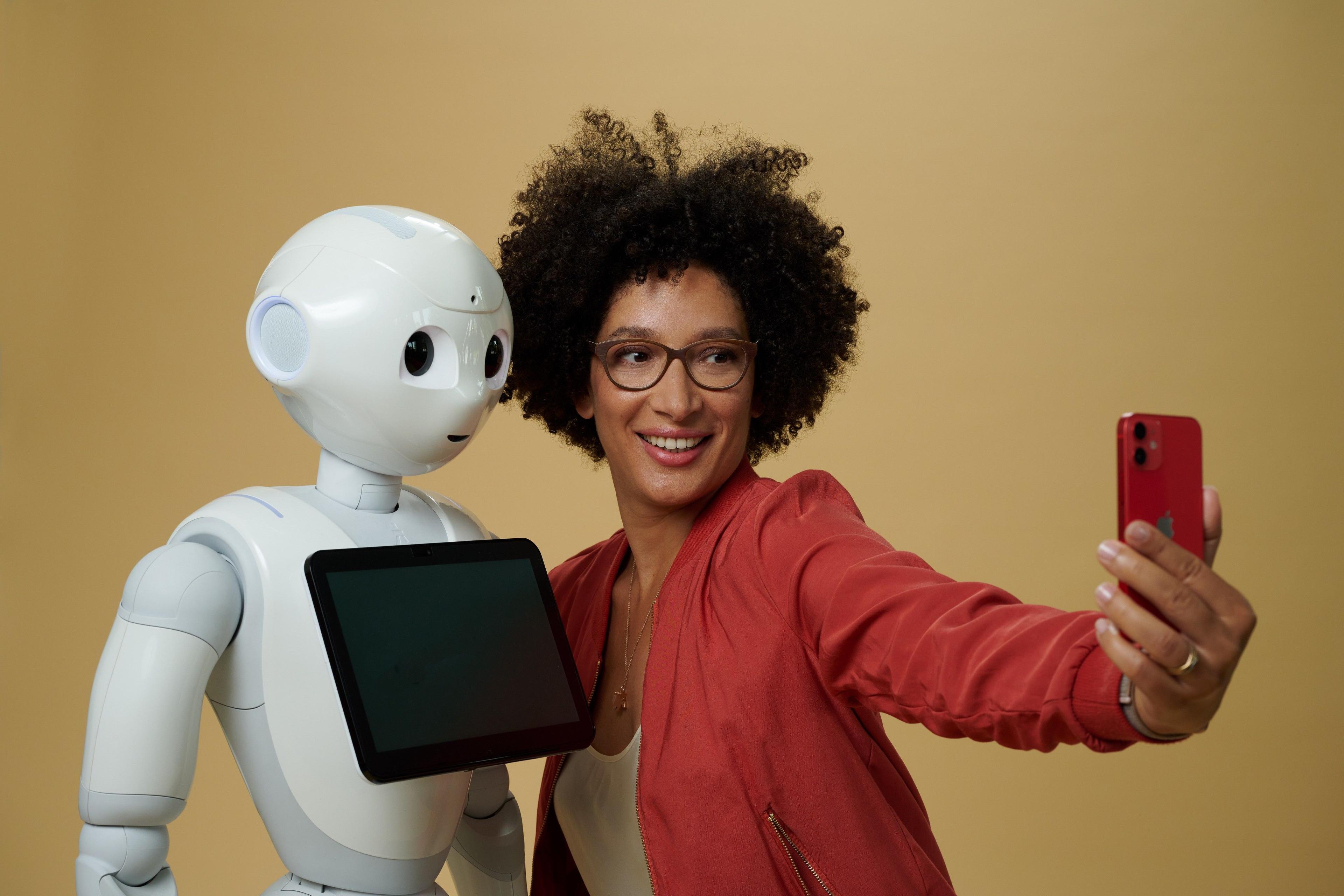 Kenza Ait Si Abbou macht ein Selfie neben einem humanoiden Roboter.