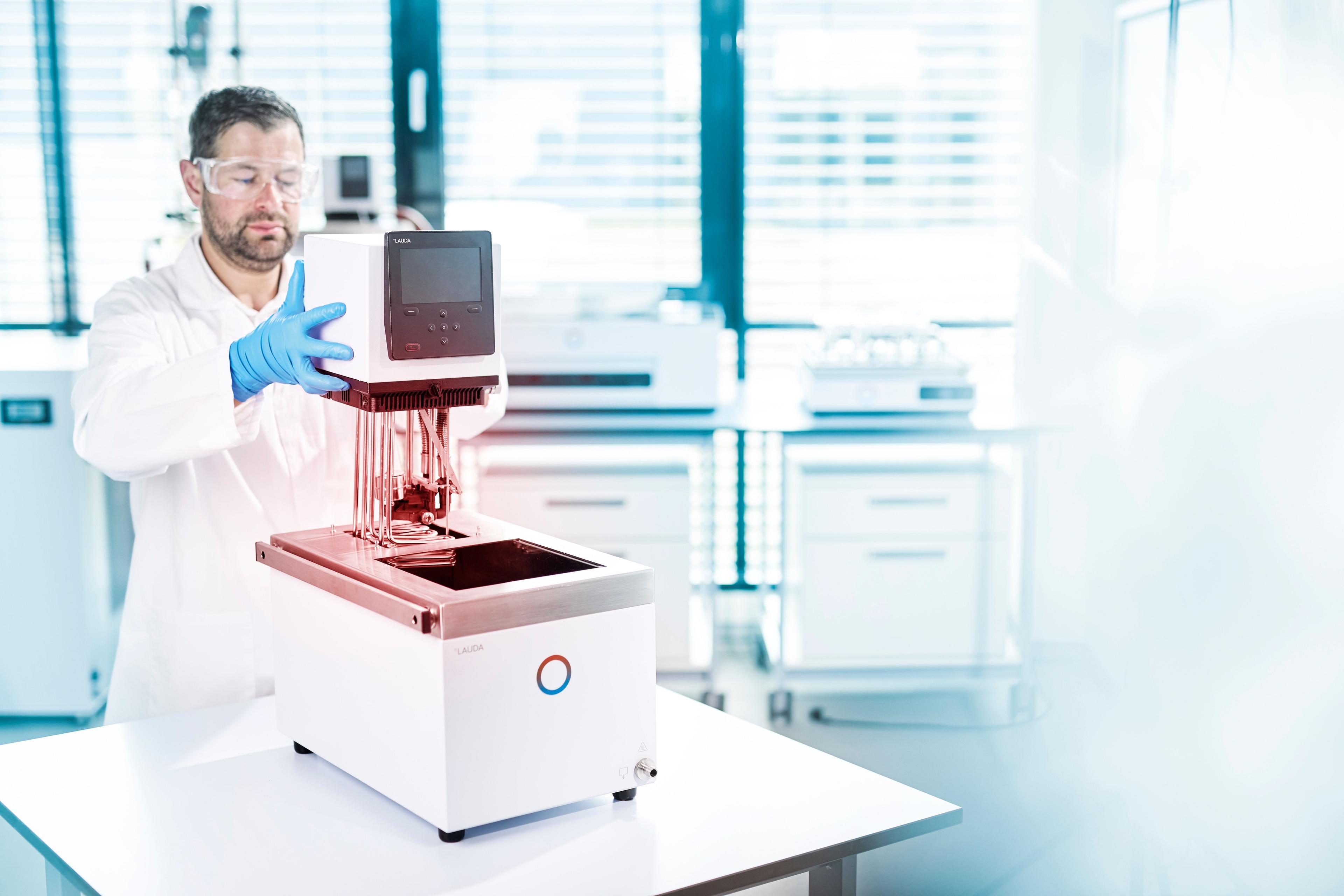 Ein Labormitarbeiter in Schutzkleidung hält den "Kopf" des Geräts in den Händen.