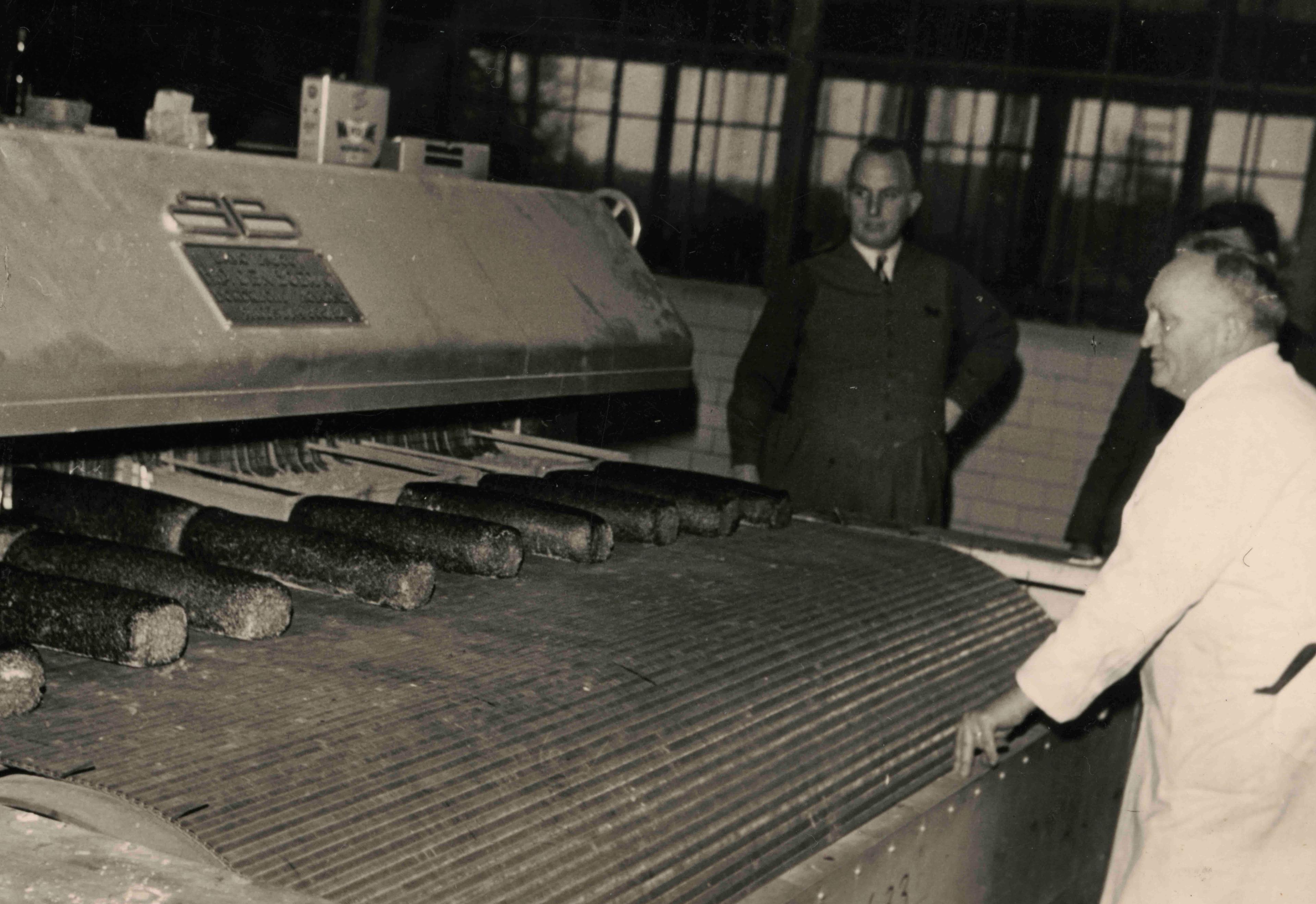 Männer stehen vor einem Industriebackofen.