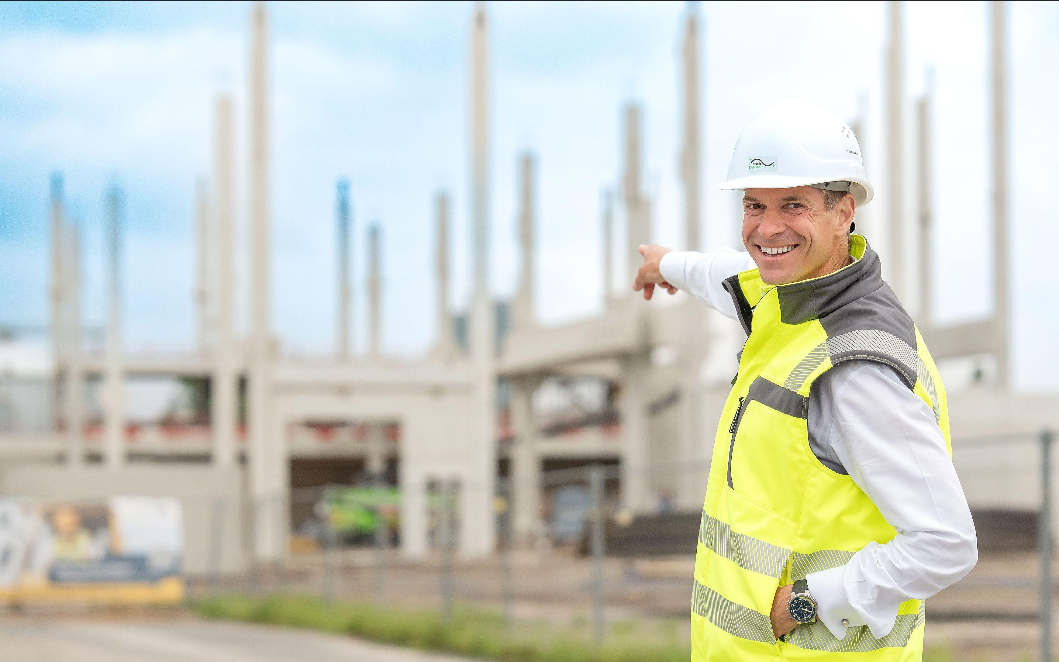 CEO Dr. Andreas Widl zeigt auf die Baustelle, auf der die Fabrik der Zukunft von Samson entsteht.